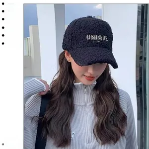 Close-up of black teddy fleece baseball cap with white UNIQUE letter embroidery
