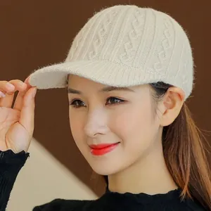 Detail of off-white knit baseball cap featuring intricate cable pattern and ribbed brim