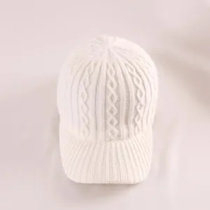 Detail of white knit baseball cap featuring classic cable knit pattern and ribbed brim