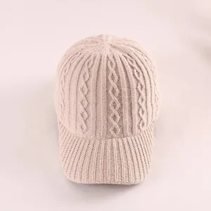 Close-up of beige cable knit pattern and ribbed brim texture on winter baseball cap