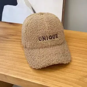 Detail of unique letter embroidery on warm beige faux shearling winter baseball cap