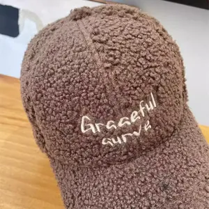 Detail of brown teddy fleece baseball cap with Graceful Curve embroidery on texture