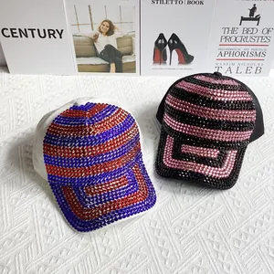Vue détaillée de casquettes de baseball à blocs de couleurs et strass sur tissu blanc