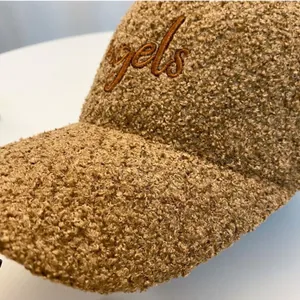 Detailed macro view of the thick brown teddy fleece texture and angels embroidery on the cap