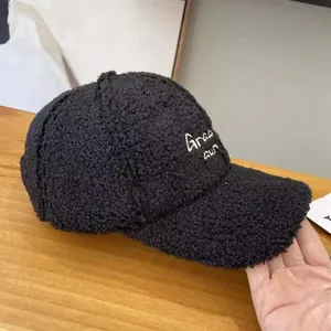 Detail of black faux shearling texture and white letter embroidery on baseball cap