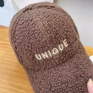 Detail of warm brown sherpa baseball cap featuring white UNIQUE embroidery texture