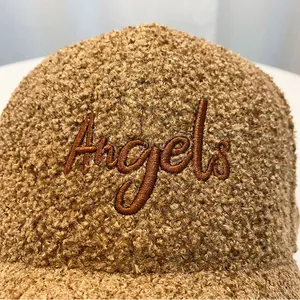 Close-up of Angels embroidery on dark camel teddy velvet baseball cap fabric