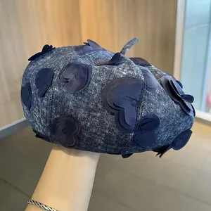 Detailed close-up of dark blue denim beret featuring 3D heart embroidery and fabric texture