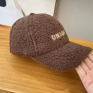 Detail of UNIQUE letter embroidery on a warm brown faux shearling baseball cap
