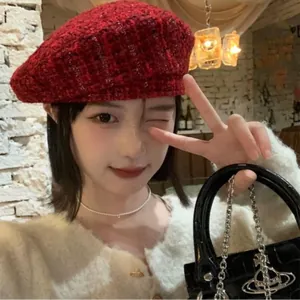 Detail of red and black tweed wool beret showing woven texture on a model
