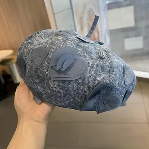 Detailed macro view of 3D embroidered heart patches on retro blue denim beret
