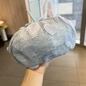 Close-up of light blue denim beret with layered heart patches and small faux diamond studs