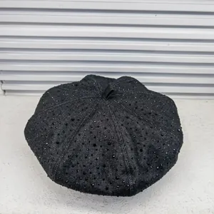 Close-up of black denim beret hat with scattered black rhinestones and top handle