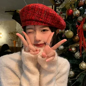 Detail of red plaid wool tweed beret hat worn by a model in a warm Christmas setting