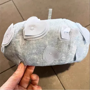 Detailed view of light blue denim beret featuring layered 3D heart-shaped embroidery patches