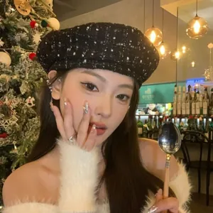 Close-up of black tweed beret styled with a soft off-shoulder plush sweater in a cafe