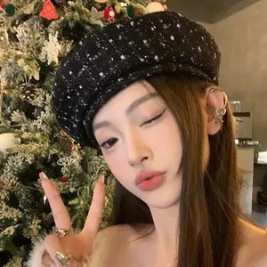 Close-up of black tweed beret texture on model with festive holiday background