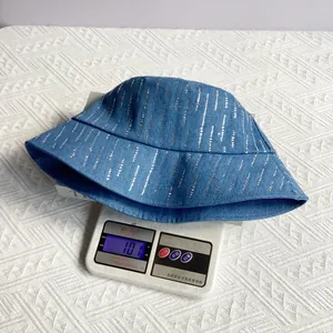 Blauwe denim vissershoed met zilveren strass steentjes weegt 101g op de weegschaal