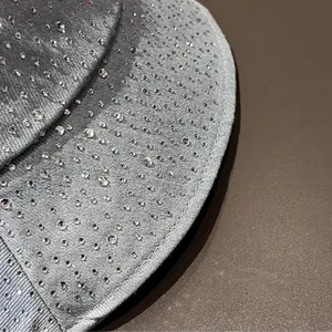 Detail of light blue denim bucket hat with sparkling rhinestones on textured fabric