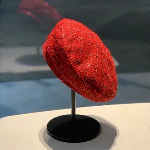 Vibrant red wool tweed beret with subtle sequins on a display stand for women