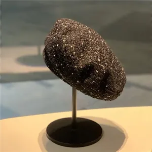 Classic dark grey wool tweed beret for women on display stand in a soft indoor setting