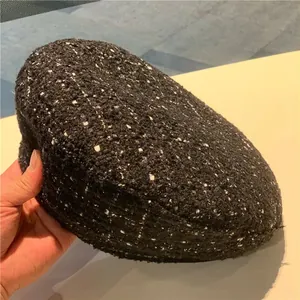 Close-up of dark tweed beret fabric showing black and gray wool texture and details