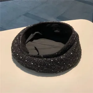 Detail of wool tweed beret showing black textured fabric and adjustable inner drawstring