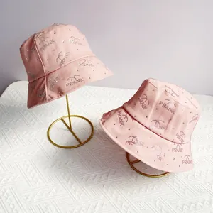 Detailed view of pink cotton bucket hats with rhinestone PRANK logo on metal stands