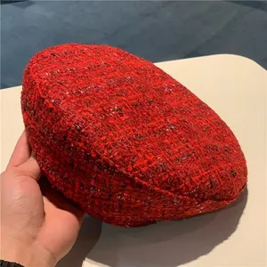 Close-up of red wool tweed beret hat showing texture of woven crimson and black yarns