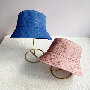 Detailed view of rhinestone M pattern on navy and pink quilted cotton bucket hats