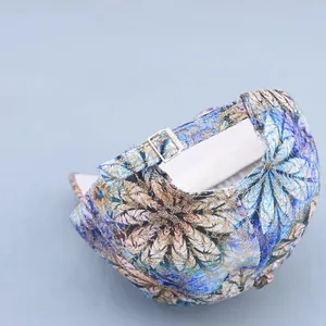 Detail of adjustable silver buckle and blue floral lace print on baseball cap fabric