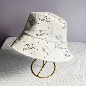 Detail of white cotton bucket hat with silver rhinestones forming PRANK and palm trees
