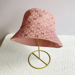 Detail showing pink bucket hat with rhinestone M pattern and luxury diamond texture