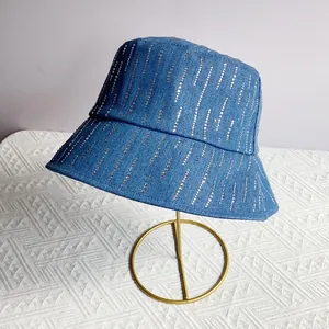 Detail van donkerblauwe denim vissershoed met zilveren strass-steentjes op metalen standaard