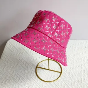 Close-up of rose red bucket hat with rhinestone M pattern on a gold display stand