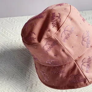 Detail shot of pink bucket hat with rhinestone branding and cotton canvas texture