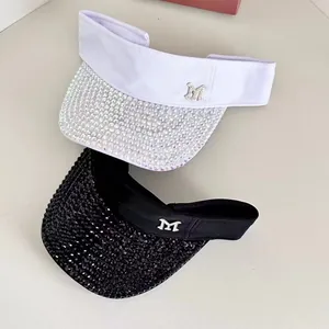 Detail view of rhinestone-encrusted visors in black and white with metal M logo