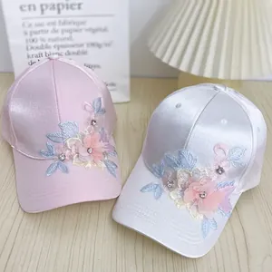 Detail of silk-like satin baseball caps with 3D floral embroidery and rhinestone accents