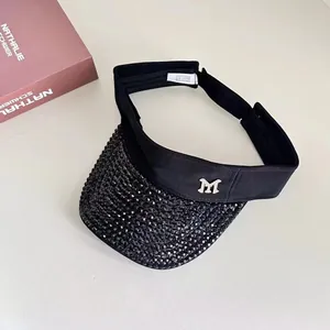 Close-up of black sun visor with sparkling rhinestones and silver M metal logo detail
