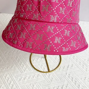 Close-up of pink bucket hat with rhinestone N logo pattern and diamond grid detail