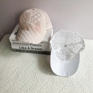 Dettaglio cappellino in pizzo rosa con farfalla di perle e trama a rete bianca