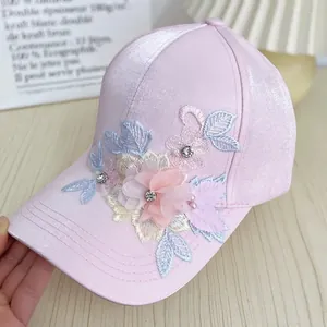 Detailed view of handmade floral embroidery with pearls and rhinestones on pink satin cap
