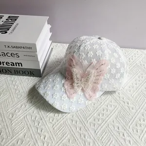 Dettaglio cappellino in pizzo bianco con farfalla rosa 3D decorata con perle eleganti