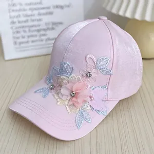 Close-up of silk-like pink baseball cap with 3D floral appliques and sequins