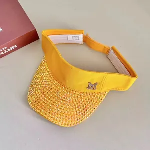 Detailed macro view of yellow sun visor with rhinestones and crystal M logo