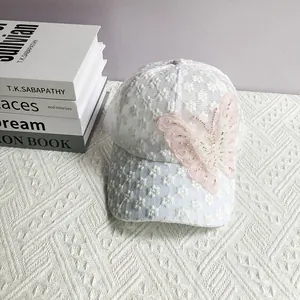Dettaglio del cappello in pizzo floreale bianco con grande farfalla 3D rosa perlata