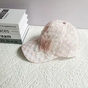 Dettaglio cappello da baseball in pizzo rosa con ricamo floreale e farfalla di perle