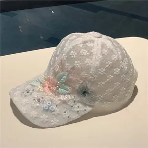Detail of white mesh baseball cap featuring lace flowers, pearls and butterfly embroidery