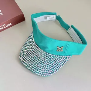 Detail of turquoise sun visor with iridescent rhinestones and silver M metal logo
