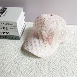 Dettaglio cappello rosa chiaro in pizzo con farfalla in mesh e decorazioni di perle